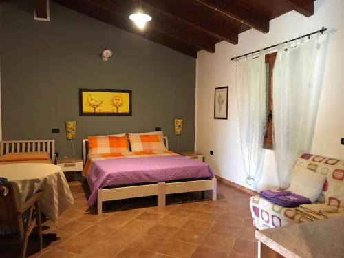 - une chambre avec un lit et une chaise dans l'établissement Agriturismo Monte Majore, à Siliqua
