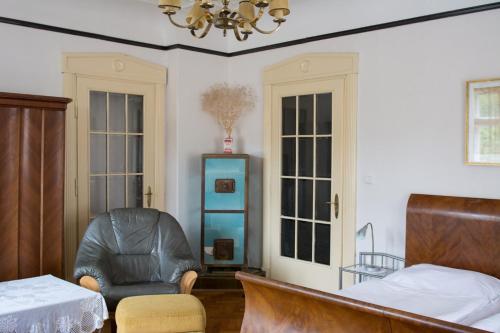 a bedroom with a chair and a bed and a chandelier at Penzion Signum Laudis in Velké Hamry