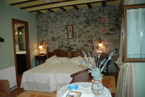 a bedroom with a bed and a stone wall at La Llobera Apartamentos in Pendueles