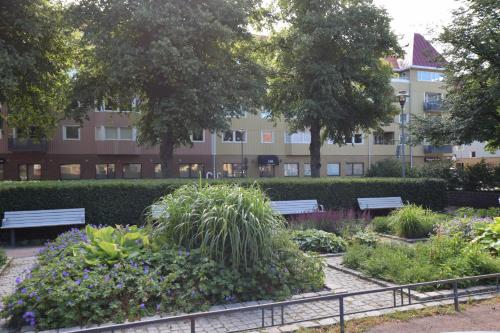 a garden with benches and flowers in front of a building at Hostel Snoozemore in Gothenburg