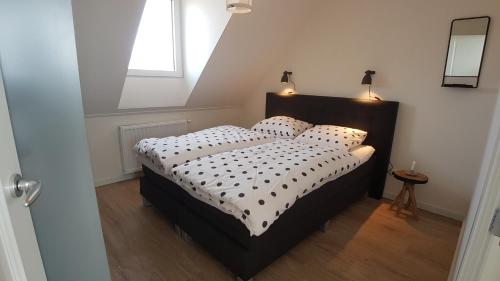 um quarto com uma cama com uma cabeceira preta e uma janela em ZON ZEE STRAND Bed by the Sea em Westkapelle