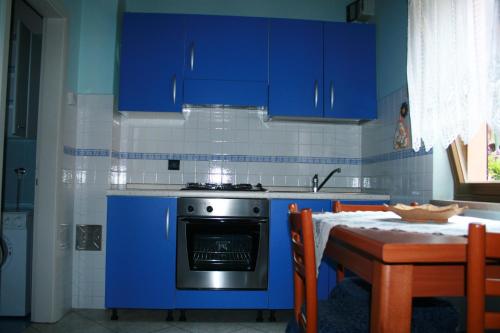 a kitchen with blue cabinets and a stove and a table at Casetta Alex Desiree in Pontebba
