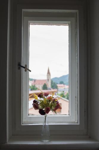 a vase with flowers sitting in a window at Penzion Signum Laudis in Velké Hamry