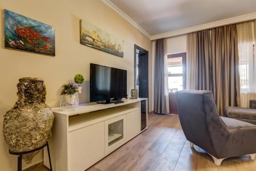 a living room with a television and a chair at Apartments PROVA in Sveti Stefan