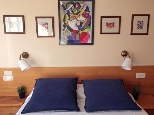 a bedroom with two blue pillows and a painting on the wall at VT Musikene Parking ESS01579 in Añorga-Lugariz