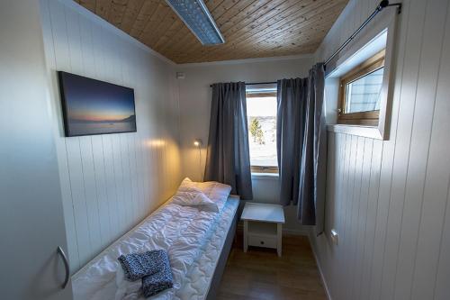 a small bed in a room with a window at Malangen Apartment in Kjerkevik