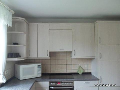 a kitchen with white cabinets and a white microwave at Ferienhaus Günter in Forchtenberg