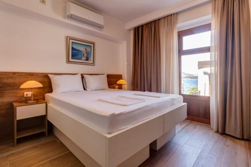 uma grande cama branca num quarto com uma janela em Apartments Langust em Sveti Stefan