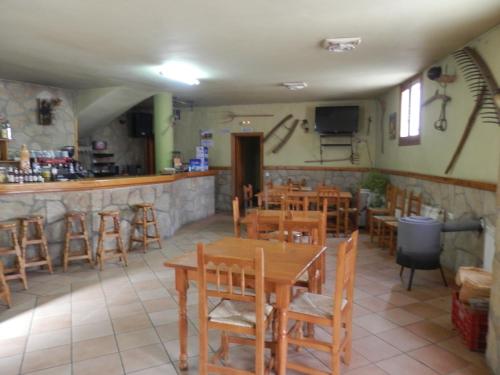 un restaurante con mesas y sillas de madera y un bar en Hostal El Portalico, en Linares de Mora