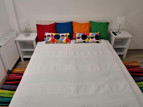 a white bed with colorful pillows in a room at Green Garden Plus Apartman in Budapest
