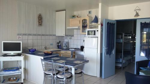 Il comprend une cuisine équipée d'un réfrigérateur blanc et d'une table avec des chaises. dans l'établissement Portes de la Rochelle, à La Rochelle