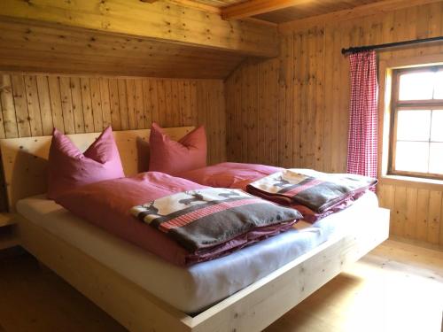 ein Bett in einem Blockhaus mit Kissen darauf in der Unterkunft UNSER VORSÄSS - Klausberg in Schwarzenberg im Bregenzerwald