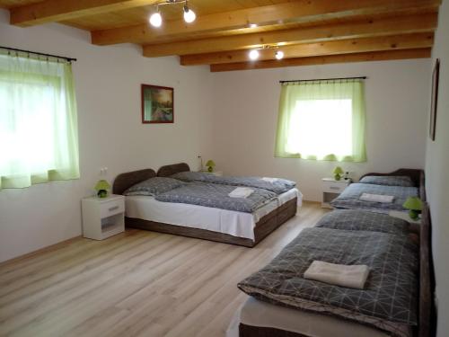 two beds in a room with wooden floors and windows at Napsugár Vendégház in Újudvar