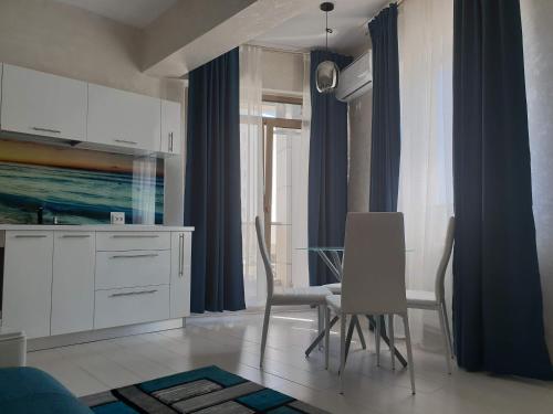 cocina con armarios blancos, mesa y sillas en Apartament Luk Twin Loft, en Mamaia