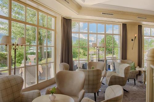 a waiting room with chairs and tables and large windows at Majestic - Unique Spa Resort in Brunico