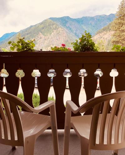 a pair of chairs on a balcony with mountains in the background at Enzian Inn in Leavenworth