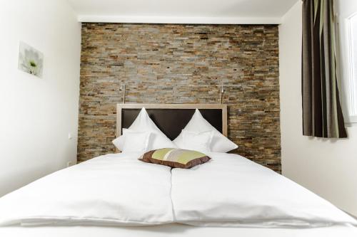 a bedroom with a white bed with a brick wall at Hotel Maxis - digitaler Self-check-in - in Karlsbad