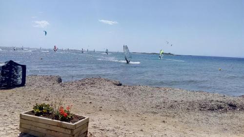 a beach with people in the water and people on a sail boat at Anna's Apartment and Studio in Artemida