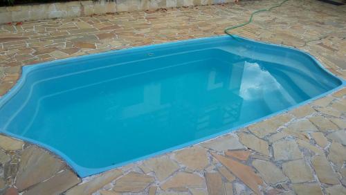 a blue swimming pool on a stone floor at Charmoso com Sauna e Piscina in Penedo