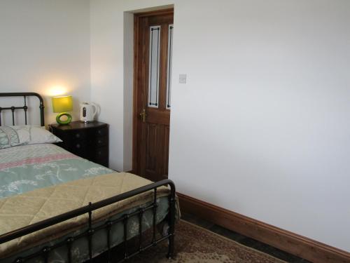 a bedroom with a bed and a white wall at Treganoon House, Lanlivery in Bodmin