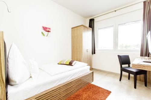 a bedroom with a bed and a desk and a chair at Hotel Maxis - digitaler Self-check-in - in Karlsbad