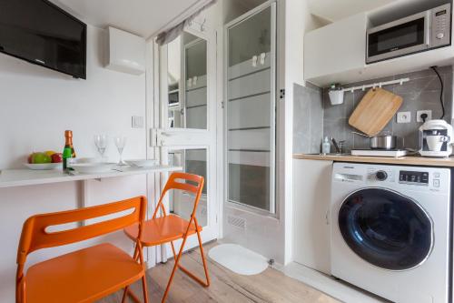 une buanderie avec lave-linge, sèche-linge et chaises orange dans l'établissement Charming Studio - Palais de Congres, à Paris
