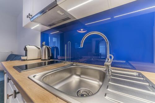 - une cuisine avec un évier et un mur bleu dans l'établissement Apartamenty Draga, à Jastarnia