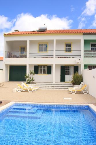 a villa with a swimming pool in front of a house at Casa Pôr do Sol in Mosteiros