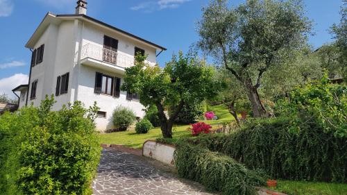 ein weißes Haus mit einem Balkon sowie Bäumen und Sträuchern in der Unterkunft Casa Vittoria in Corsanico-Bargecchia