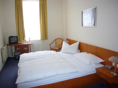 a bedroom with a large white bed with a window at Hotel Deutsches Haus in Kaub
