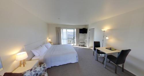 Cette chambre comprend un lit, un bureau et une table. dans l'établissement Westport Spa Motel, à Westport