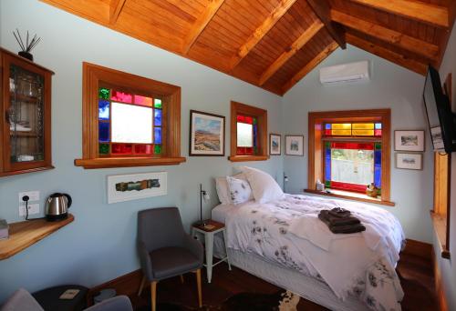 a bedroom with a bed and a chair and windows at Maungakawa Villa in Cambridge