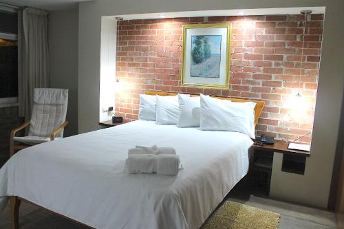 a bedroom with a large white bed with a brick wall at Apartamentos Reforma in Guatemala