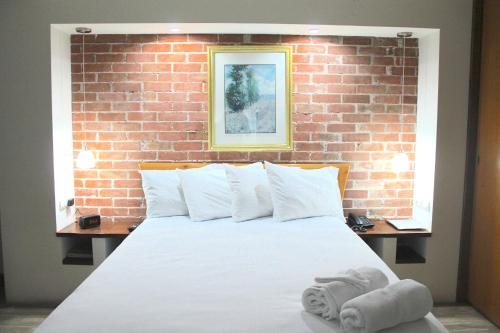a bedroom with a white bed with a brick wall at Apartamentos Reforma in Guatemala