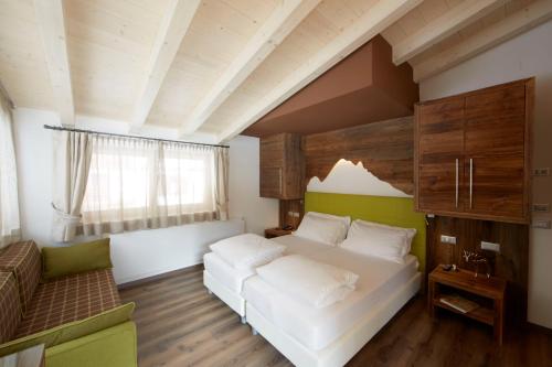 a bedroom with a white bed and a green wall at Chalet Vites Mountain Hotel in Canazei