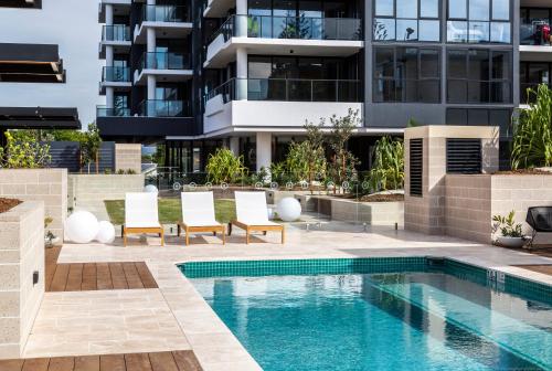 an apartment with a swimming pool in front of a building at Boardwalk Burleigh Beach - Official in Gold Coast