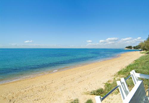 a beach with a white fence and the ocean at The Sebel Brisbane Margate Beach in Redcliffe