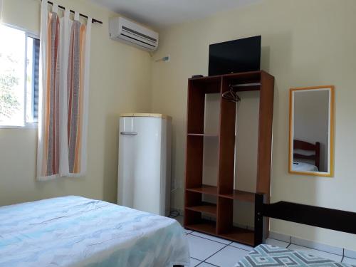 a bedroom with a refrigerator and a television in it at Atlântico in Maresias