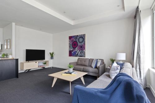 a living room with a couch and a tv at Nook Melbourne Apartments : Collins Street - Melbourne CBD in Melbourne