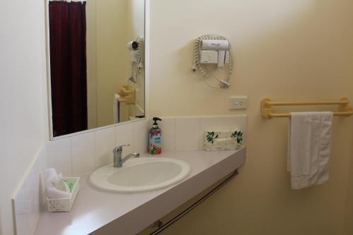 a white sink sitting under a mirror in a bathroom at Parkside Motel & Licensed Restaurant in Ayr