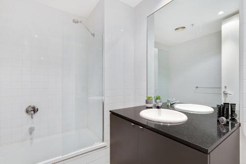 a white bathroom with a sink and a shower at Nook Melbourne Apartments : Collins Street - Melbourne CBD in Melbourne