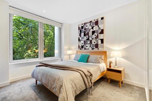 a bedroom with a bed and two windows at Nook Melbourne Apartments : Collins Street - Melbourne CBD in Melbourne