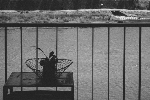 a plant in a basket on a table in front of a fence at Wuz Kamogawa in Kyoto