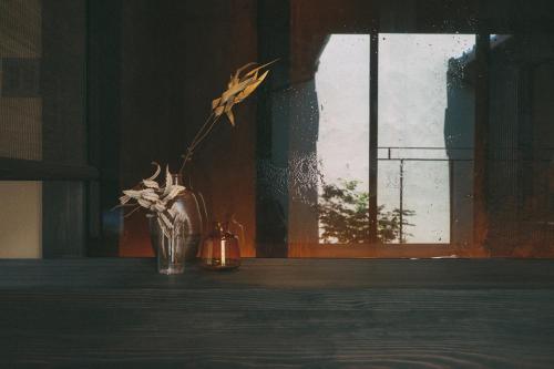 a vase of flowers on a table with a window at Wuz Kamogawa in Kyoto