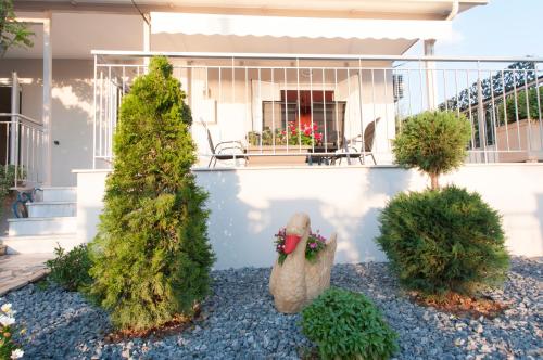 a garden with trees and a chicken statue in front of a house at A perfect summer destination next to the sea in Mikrá Mandínia