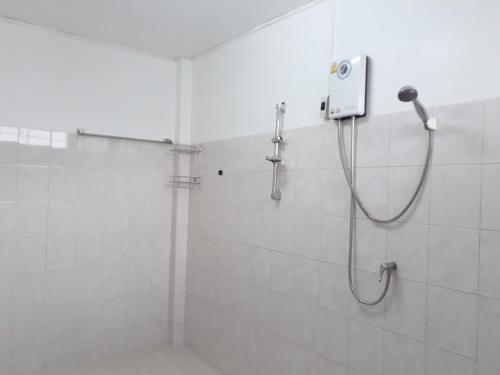 a shower in a white tiled bathroom at Mae Rampung Beach House คาราโอเกะและสระเด็ก in Rayong