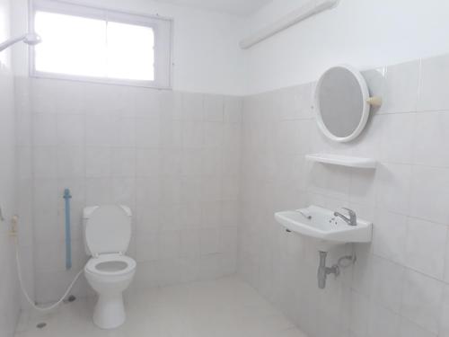 a white bathroom with a toilet and a sink at Mae Rampung Beach House คาราโอเกะและสระเด็ก in Rayong