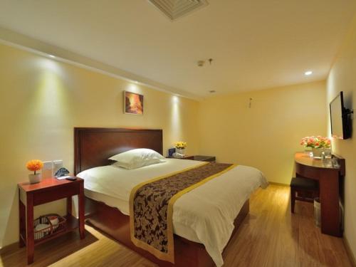a bedroom with a bed and two tables and a television at Greentree Alliance Beijing West Railway Station Zhanqian North Square Hotel in Beijing