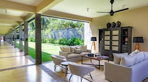 a living room with white furniture and large sliding glass doors at Taru Villas The Long House - Bentota in Bentota