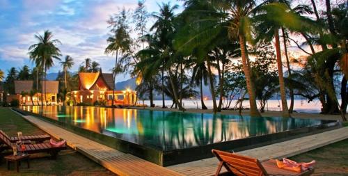 a swimming pool with a house and palm trees at Summer time villa in Trat